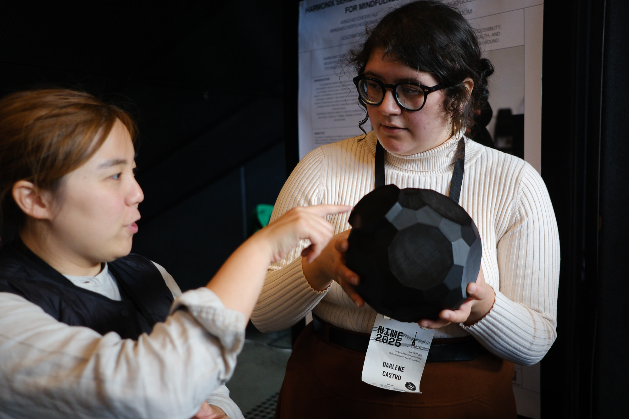 Cheryl Hui demonstrating "Harmonix Series" to Darlene Castro at Posters 1.